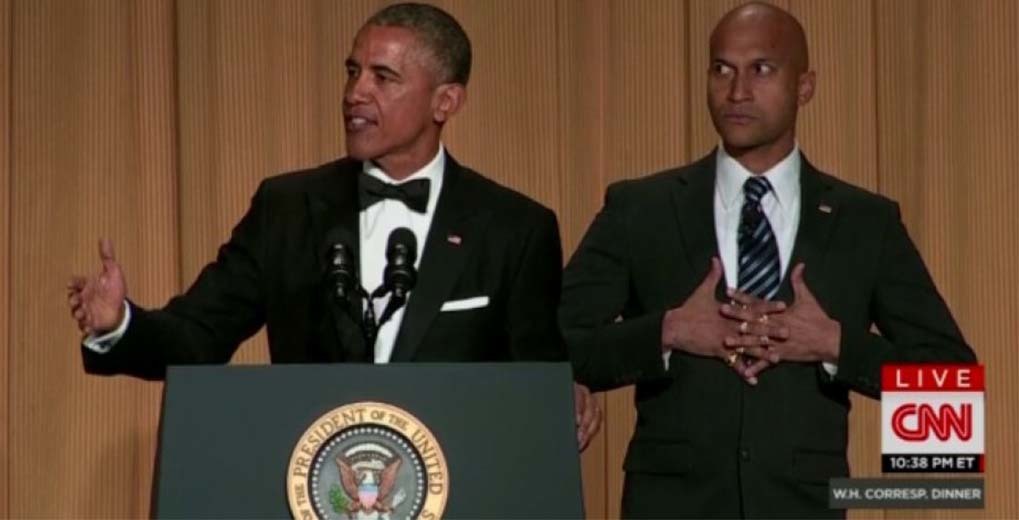 Barack Obama talking at podium with Michael Keegan Key next to him with stern look